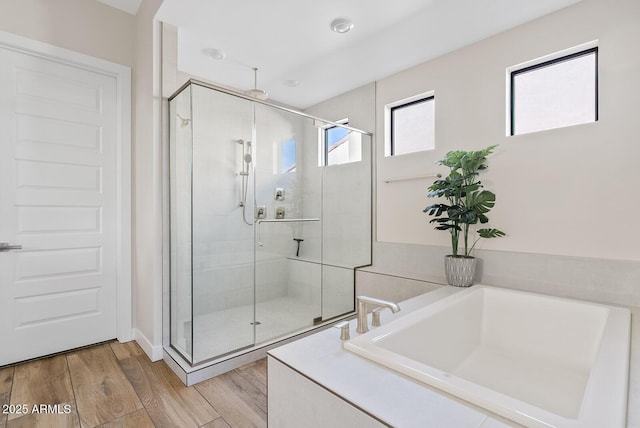 full bathroom with a stall shower, a garden tub, and wood finished floors