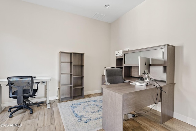 office with baseboards and light wood-style flooring