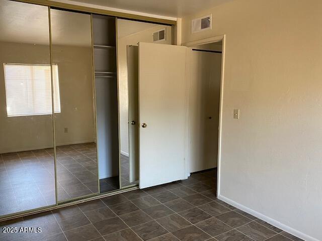 27 W Concorda Dr Unit 104, Tempe, AZ 85282 - unfurnished bedroom featuring a closet and dark tile patterned floors