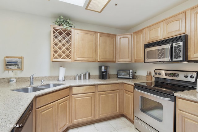 kitchen featuring stainless steel appliances, light brown cabinets, a sink, and light tile patterned floors