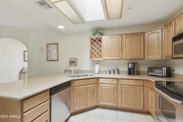 kitchen with light brown cabinets, a toaster, stainless steel appliances, a sink, and light stone countertops