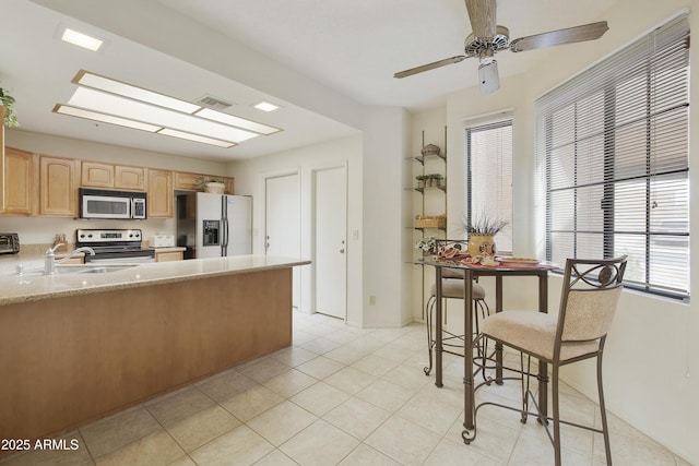 kitchen featuring stainless steel appliances, a skylight, a sink, visible vents, and light brown cabinetry