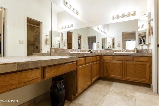 bathroom with double vanity, a shower, a sink, and tile patterned floors