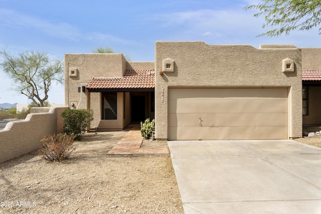 pueblo revival-style home featuring stucco siding, concrete driveway, an attached garage, fence, and a tiled roof