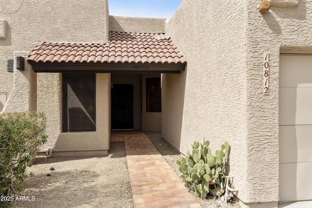 property entrance featuring a tiled roof and stucco siding