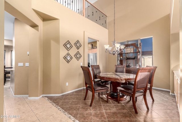 dining room featuring a towering ceiling, baseboards, a chandelier, and tile patterned floors