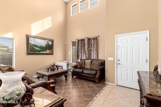 living room with light tile patterned flooring, a towering ceiling, and baseboards