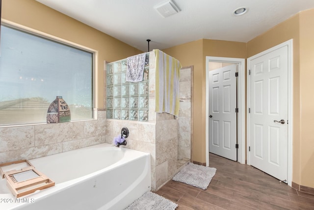 bathroom featuring a garden tub, visible vents, walk in shower, and wood finished floors