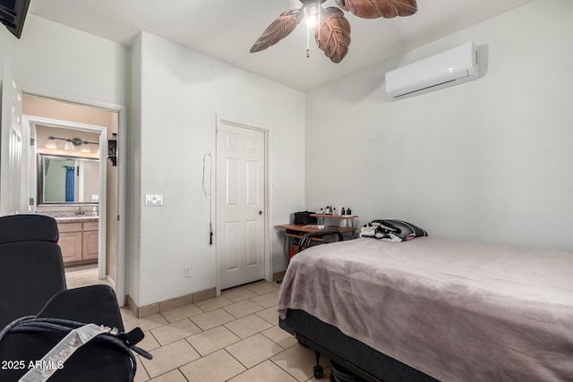 bedroom featuring light tile patterned floors, connected bathroom, a ceiling fan, baseboards, and an AC wall unit