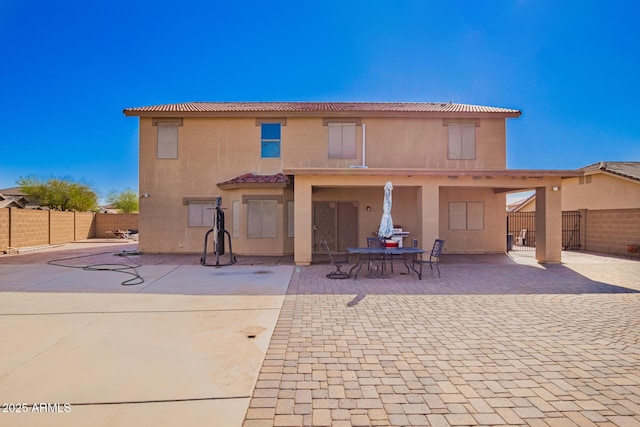 rear view of house with a fenced backyard, a tile roof, a patio, and stucco siding