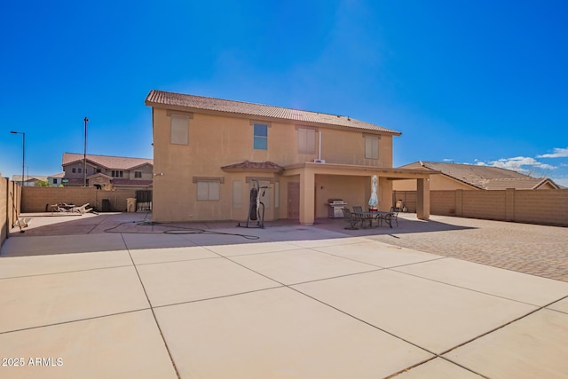 rear view of property featuring a patio area, a fenced backyard, and stucco siding