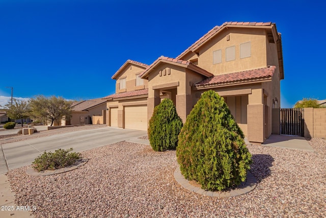 mediterranean / spanish house featuring a gate, driveway, an attached garage, and stucco siding