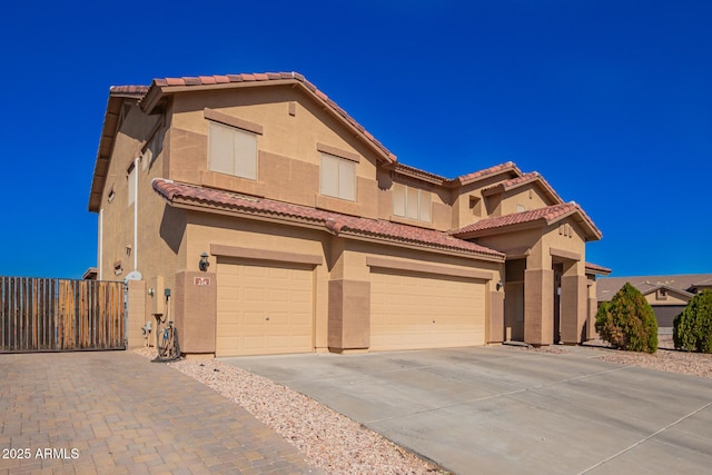 mediterranean / spanish-style home featuring a garage, concrete driveway, fence, and stucco siding