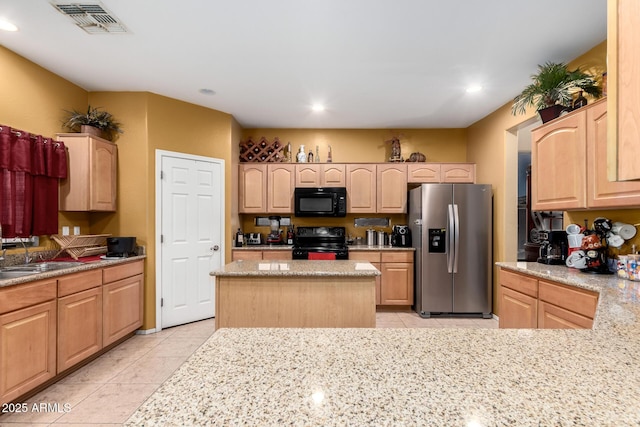 kitchen with light tile patterned flooring, a sink, visible vents, light brown cabinetry, and black appliances