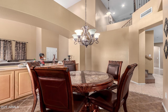 dining space with visible vents, dark tile patterned floors, a towering ceiling, and an inviting chandelier