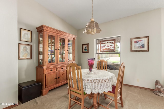 dining area featuring an inviting chandelier, light colored carpet, and lofted ceiling