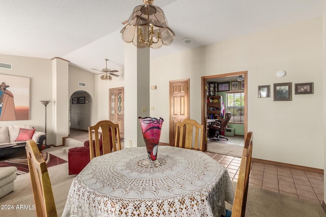 tiled dining space featuring ceiling fan with notable chandelier and lofted ceiling