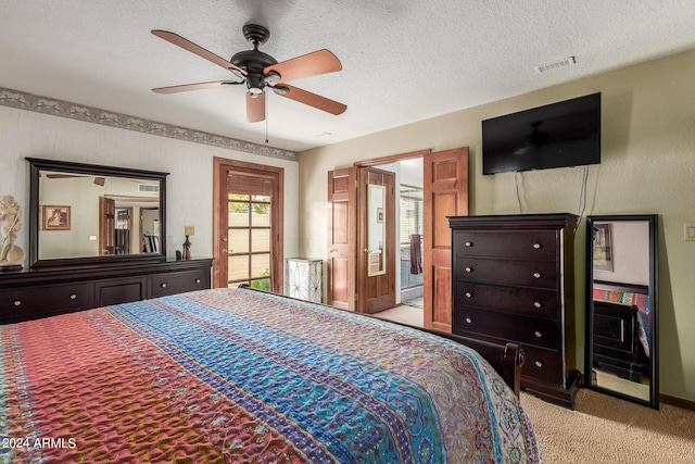 bedroom featuring ceiling fan, ensuite bathroom, light colored carpet, and a textured ceiling