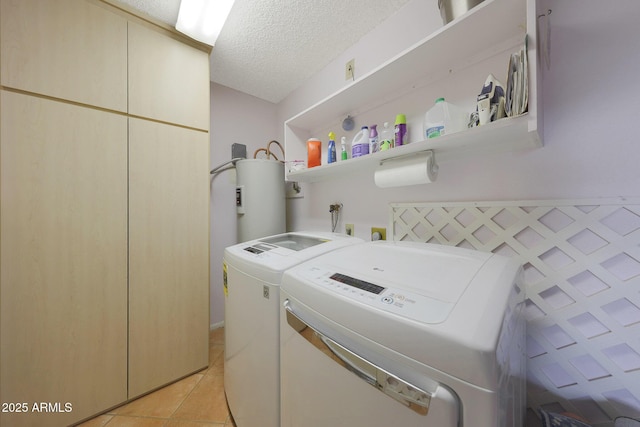 washroom featuring laundry area, washer and clothes dryer, a textured ceiling, water heater, and light tile patterned flooring