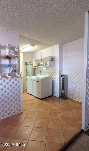 washroom with light tile patterned floors, a textured ceiling, electric water heater, laundry area, and independent washer and dryer