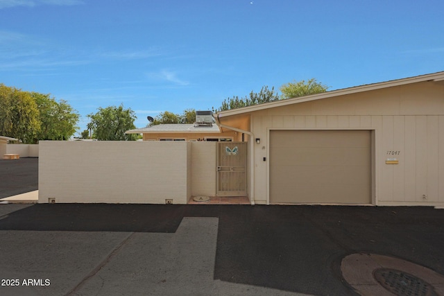 view of front of home with aphalt driveway, a gate, fence, and an attached garage