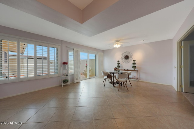 unfurnished dining area featuring tile patterned flooring, a ceiling fan, and baseboards