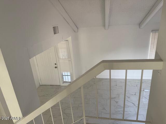 staircase featuring a textured ceiling and beam ceiling