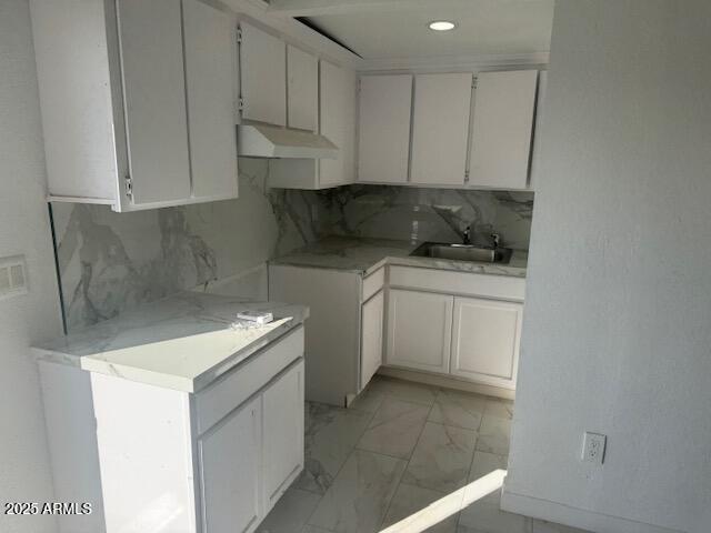 kitchen with white cabinetry, sink, and backsplash