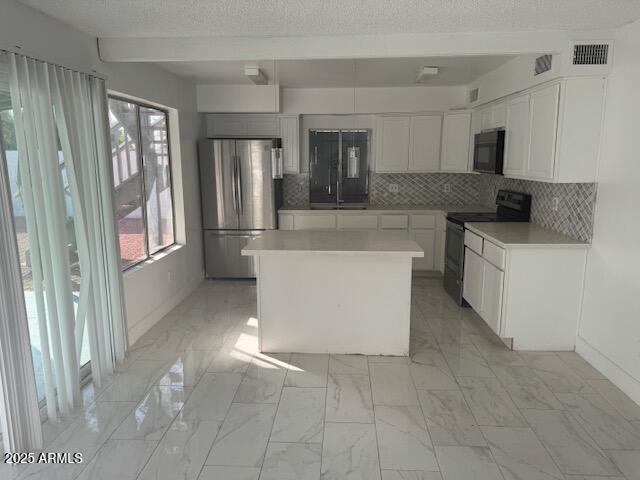 kitchen featuring backsplash, black appliances, a center island, and white cabinets