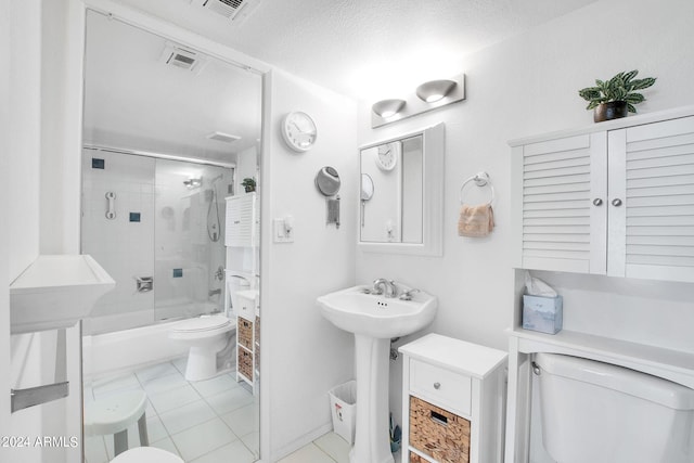 full bathroom featuring tile patterned flooring, toilet, bath / shower combo with glass door, a textured ceiling, and sink