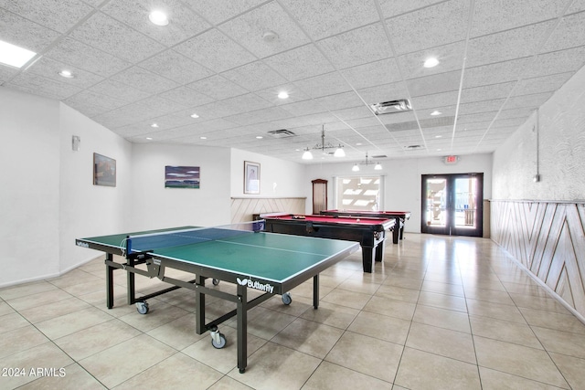 recreation room with a paneled ceiling, french doors, and light tile patterned floors