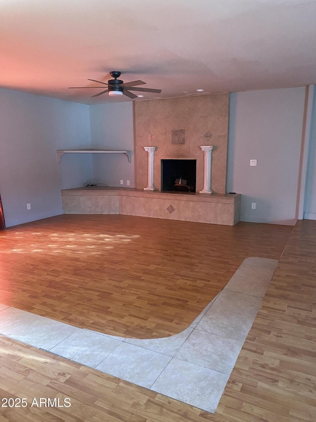 unfurnished living room with ceiling fan, a fireplace, and light hardwood / wood-style flooring