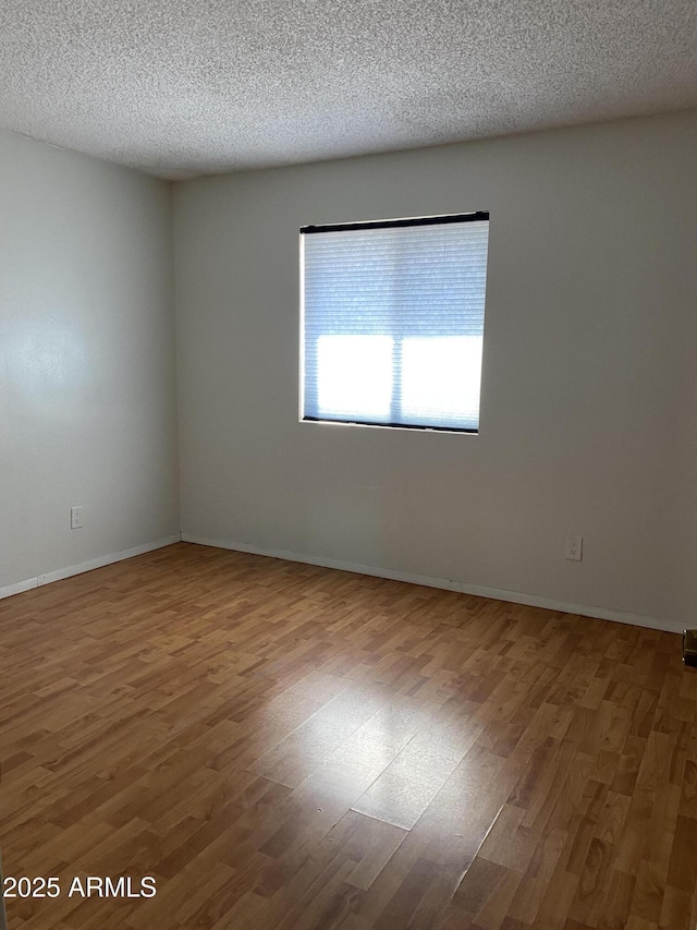 unfurnished room with wood-type flooring and a textured ceiling