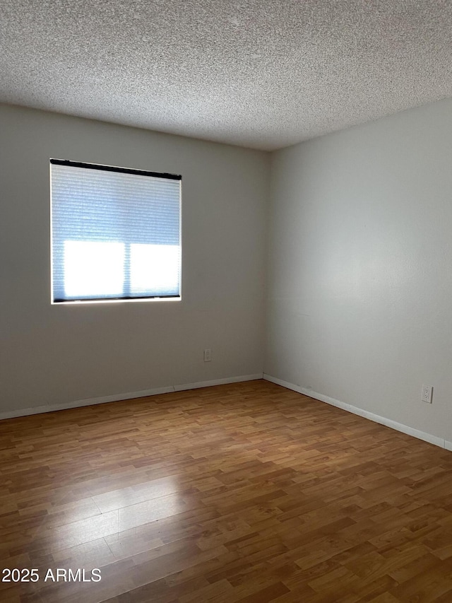 unfurnished room featuring hardwood / wood-style flooring and a textured ceiling