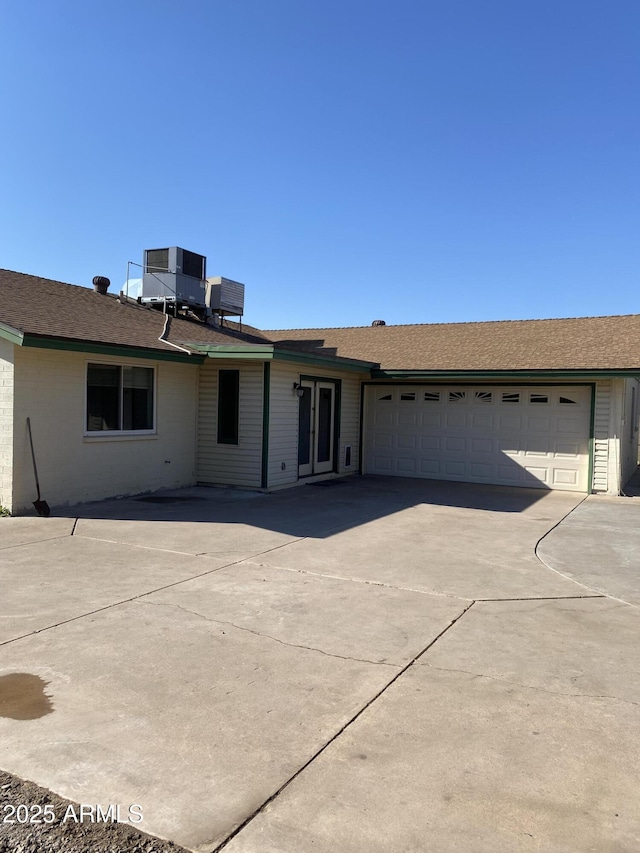 single story home featuring cooling unit and a garage