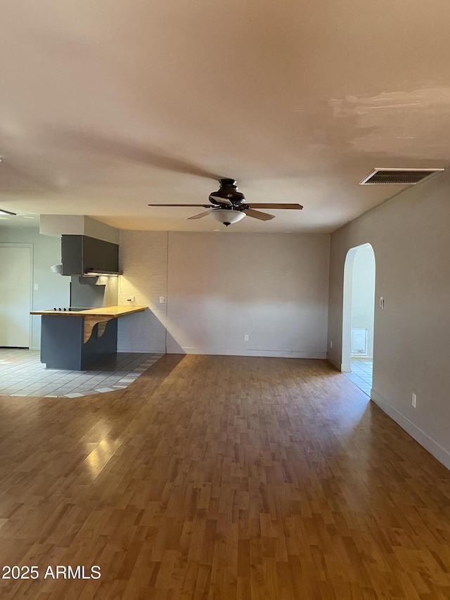 unfurnished living room featuring wood-type flooring and ceiling fan