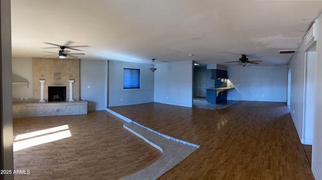 unfurnished living room with dark wood-type flooring, a fireplace, and ceiling fan