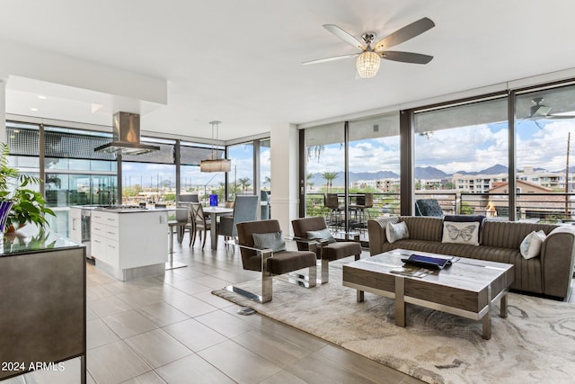 tiled living room featuring ceiling fan, a wall of windows, and a mountain view