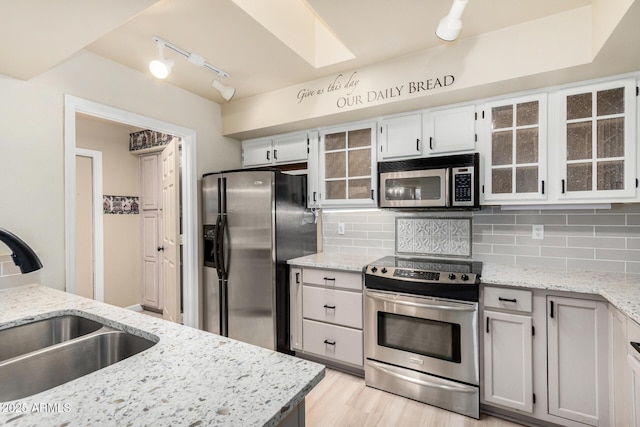 kitchen with sink, white cabinetry, stainless steel appliances, tasteful backsplash, and light stone countertops