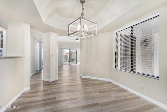 unfurnished dining area featuring an inviting chandelier and light hardwood / wood-style flooring