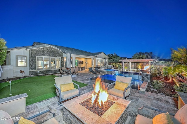 view of patio / terrace featuring a swimming pool with hot tub and a fire pit