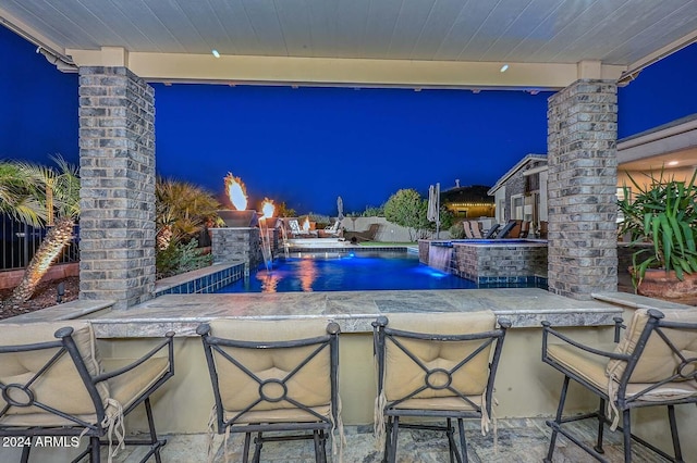 pool at twilight featuring pool water feature