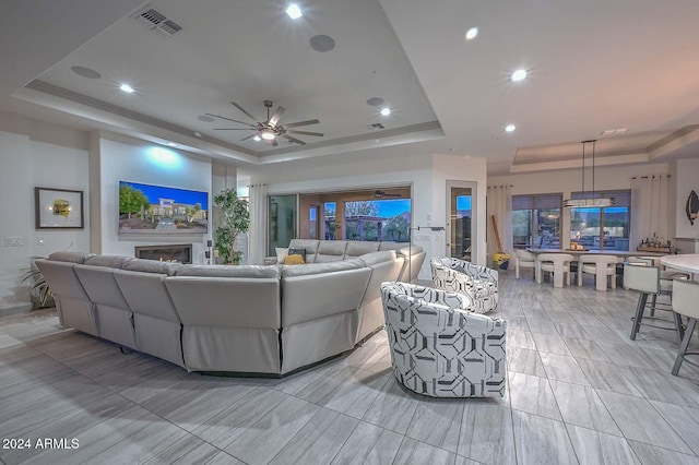 living room featuring ceiling fan and a raised ceiling