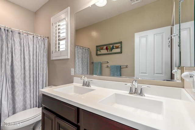 bathroom featuring a sink, visible vents, toilet, and double vanity