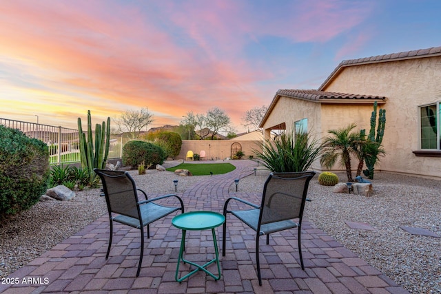 patio terrace at dusk featuring a fenced backyard