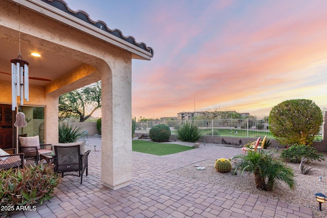 patio terrace at dusk featuring a fenced backyard