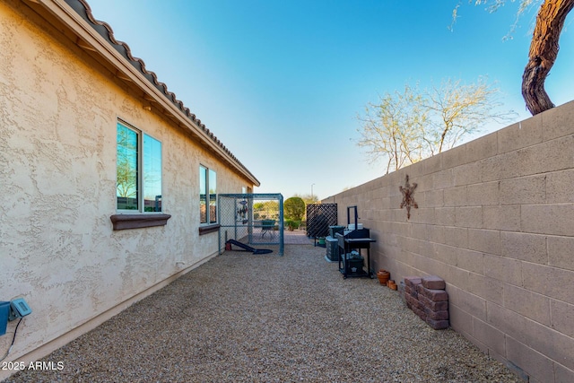 exterior space with stucco siding, a tile roof, and a fenced backyard