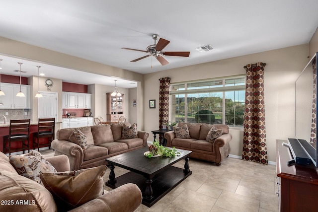 living area featuring light tile patterned flooring, a ceiling fan, visible vents, and baseboards