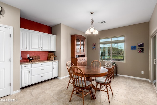 dining room with a chandelier, visible vents, and baseboards