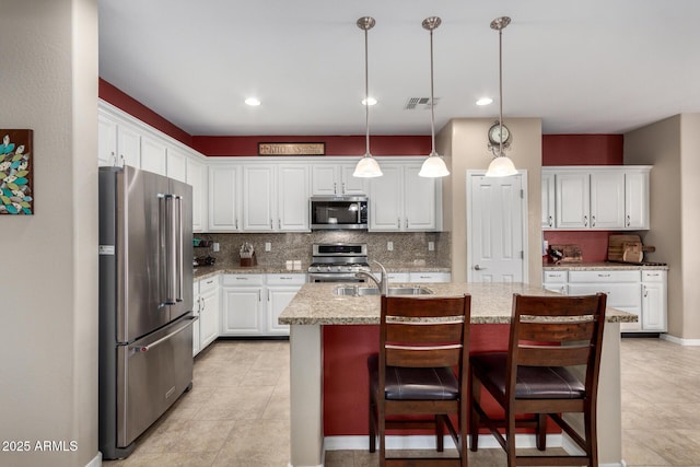 kitchen with decorative backsplash, visible vents, appliances with stainless steel finishes, and a sink